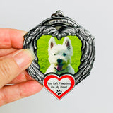 Close-up of a hand holding a pet photo angel wings ornament showing silver detailing and red heart design.