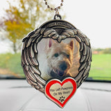 Pet memorial angel wings ornament hanging from a car mirror with a small white dog photo and red heart charm.