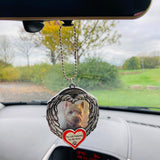 Pet memorial angel wings ornament hanging from a car mirror with a small white dog photo and red heart charm.