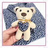 Small memorial bear made from clothing heart detail held in hand for comfort keepsake