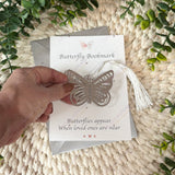 Hand holding silver butterfly memorial bookmark with tassel, sympathy gift for loss and bereavement.