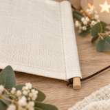 Close-up of the cream poly-linen remembrance pennant showing the fabric texture, wooden dowel and brown hanging cord.