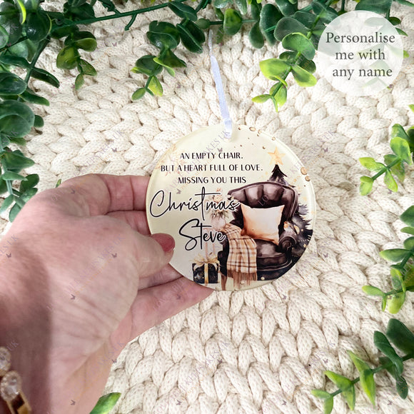 Hand holding an acrylic memorial bauble featuring the “Empty Chair” Christmas design, personalised with the name Steve, displayed on a knitted cream blanket with greenery.