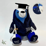 Graduation keepsake dog made from NHS nurse's uniform, wearing a mortarboard and gown, holding a scroll. Handmade by Loveable Keepsakes.