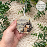 Empty Chair Christmas bauble personalised with the name Nanna, featuring an armchair, Christmas tree and robin design. Acrylic memorial bauble shown held in hand.