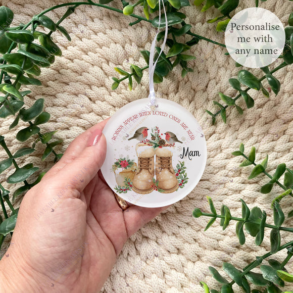 Hand holding a personalised acrylic robin remembrance bauble featuring two robins perched above winter boots, with the words “Robins appear when loved ones are near” and a custom name – memorial keepsake decoration.