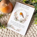 Robin remembrance enamel pin and A6 keepsake poem card styled with a robin ornament, recycled brown envelope, greenery and cream knitted background.