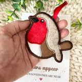 Close-up of a large embroidered felt robin with red breast and brown wings on a remembrance backing card.