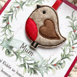 Close-up of a felt robin Christmas tree ornament mounted on a personalised remembrance poem card reading “Mum.