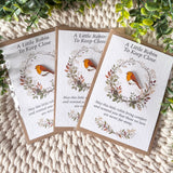 Three finished examples of the robin remembrance enamel pin and A6 keepsake poem card, each presented with a recycled brown envelope in a clear protective sleeve.