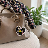 Fabric memory heart keyring attached to a handbag, with the loved one’s matching floral top displayed nearby.