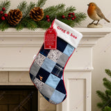 Handmade memory patchwork Christmas stocking made from loved one’s clothing, featuring embroidered name and robin detail, displayed on white fireplace with festive garland and pinecones.