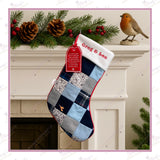 Handmade memory patchwork Christmas stocking made from loved one’s clothing, featuring embroidered name and robin detail, displayed on white fireplace with festive garland and pinecones.